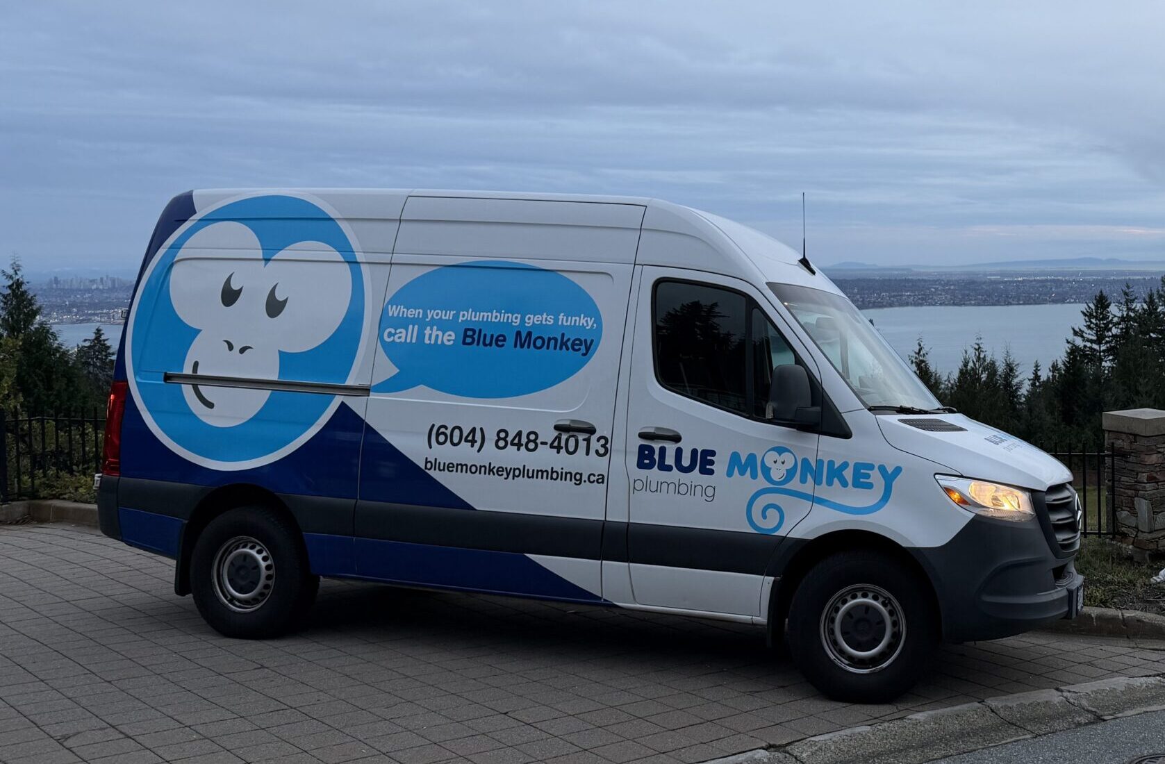 Blue Monkey Plumbing van at a British Properties home in West Vancouver with ocean views in the background